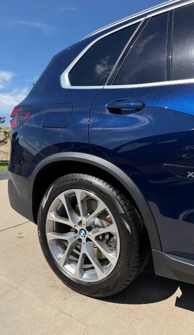 Close-up of a dark blue BMW X5 rear quarter with shining paint and dressed tire