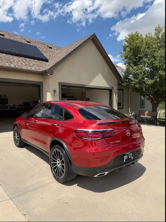 Red Mercedes GLE viewed from the left rear with glossy paint in a home driveway